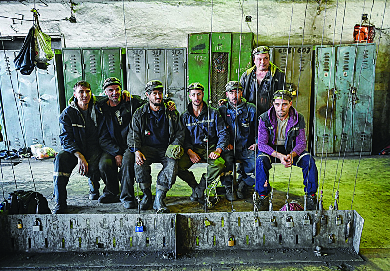 Miners pose for a photo in the locker room prior to entering the shift at Lonea coal mine in Petrila, Romania, one of the coal mining cities located in the mountain area of Valea Jiului (The Jiu's Valley) November 24, 2020. - In the past, the miners have been supported by the communist regime and then by former social-democratic president Ion Iliescu, who had more than once used them in the early 1990s to subdue his opponents who have taken to the streets.From some 54,000 miners thirty years ago, Jiu Valley has now only 4,500. (Photo by Daniel MIHAILESCU / AFP)