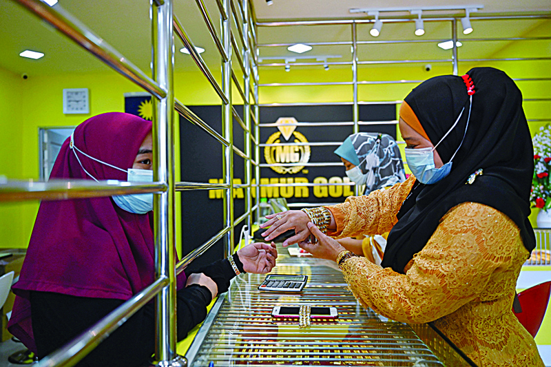 This picture taken on November 8, 2020 shows a customer trying on a bracelet at the Makmur Gold shop in Kota Bharu in Malaysia's Kelantan state. - Demand for the safe-haven commodity has soared in Malaysia during the coronavirus pandemic and it is not only professional investors who are cashing in, but small businesses too. (Photo by Mohd RASFAN / AFP) / TO GO WITH Health-virus-Malaysia-economy-gold, FOCUS by Patrick Lee