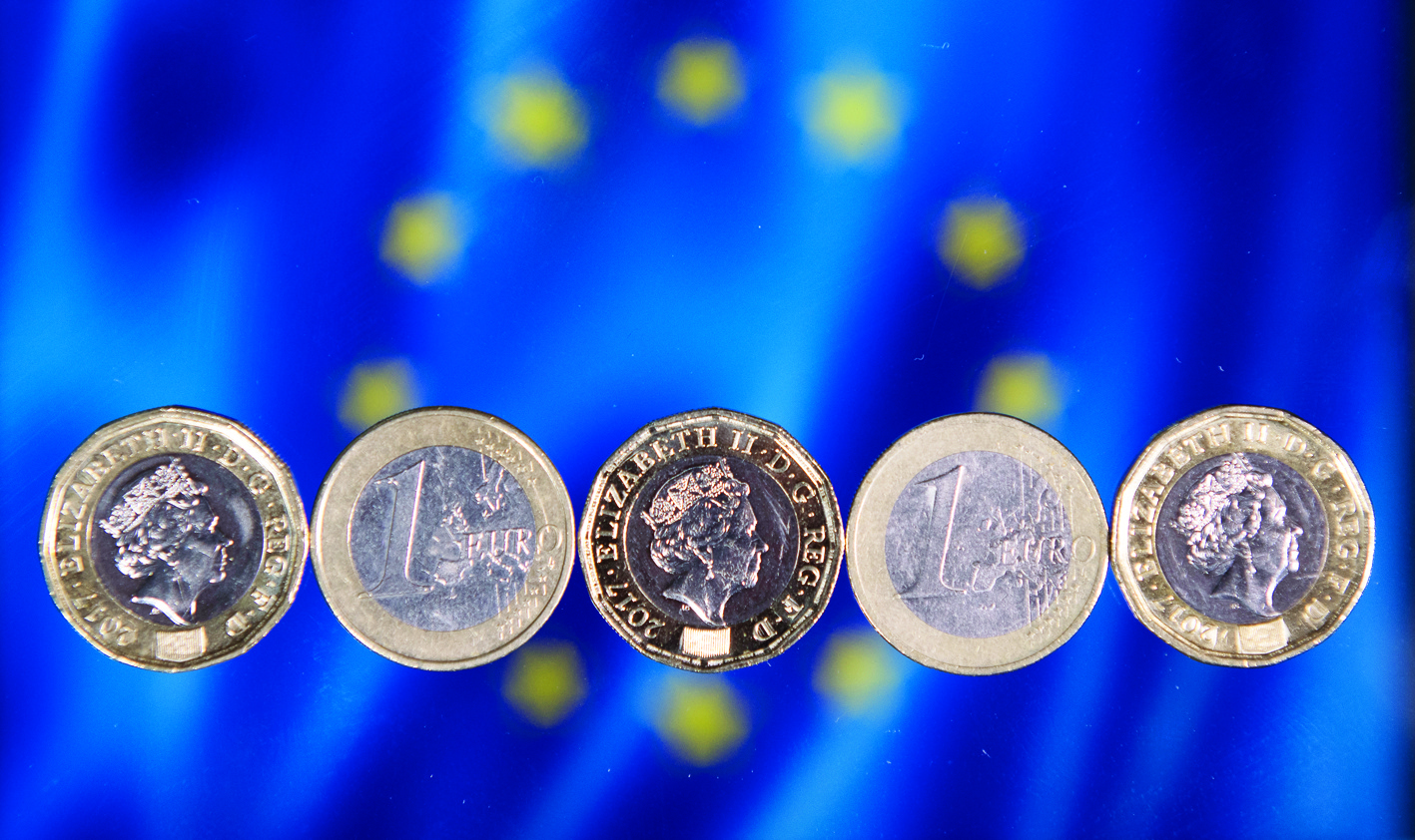 (FILES) In this file photo taken on December 14, 2017 British one pound sterling coins and one Euro coins are arranged in front of the European Union flag in a photograph in London on December 14, 2017. - The pound slumped more than one percent against the dollar and euro on on December 7, 2020 with post-Brexit trade talks between Britain and the European Union on a knife-edge. (Photo by Justin TALLIS / AFP)