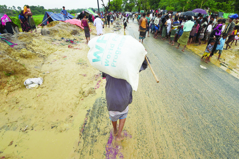 (FILES) In this file photo taken on September 17, 2017 A Rohingya Muslim refugee carries a rice bag along a road near Balukhali refugee camp near the Bangladesh town of Gumdhum on September 17, 2017. - Adjusting to a world where travel is hampered by the pandemic, this year's Nobel laureates will receive their prizes at home this week following the cancellation of the traditional Stockholm and Oslo ceremonies. he prestigious Nobel Peace Prize, which is normally handed out in Norway's capital Oslo, will be presented in Rome on December 10, 2020 to World Food Programme executive director David Beasley at a ceremony broadcast online. (Photo by DOMINIQUE FAGET / AFP)
