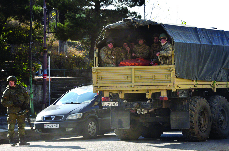 Azerbaijani soldiers ride in the back of a truck through the town of Lachin on December 1, 2020. - Azerbaijani soldiers on December 1 hoisted their country's flag in the final district given up by Armenia under a peace deal that ended weeks of fighting over the disputed Nagorno-Karabakh region. A column of Azerbaijani military trucks entered the Lachin district overnight, taking over the last of three regions around Karabakh handed over by Armenia under the Russian-brokered agreement. (Photo by Karen MINASYAN / AFP)