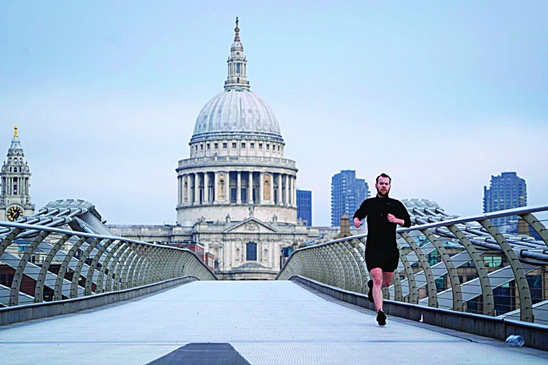 A jogger runs across the Millennium Bridge across the River Thames with St Paul's Cathedral in the background in London on December 31, 2020 on the day that the Brexit transition period ends and Britain leaves the EU single market and customs union four-and-a-half years after voting to leave the bloc. - Brexit becomes a reality on on December 31 as Britain leaves Europe's customs union and single market, ending nearly half a century of often turbulent ties with its closest neighbours. The UK's tortuous departure from the European Union takes full effect when Big Ben strikes 11:00 pm (2300 GMT) in central London, just as most of the European mainland ushers in 2021 at midnight. (Photo by Niklas HALLE'N / AFP)