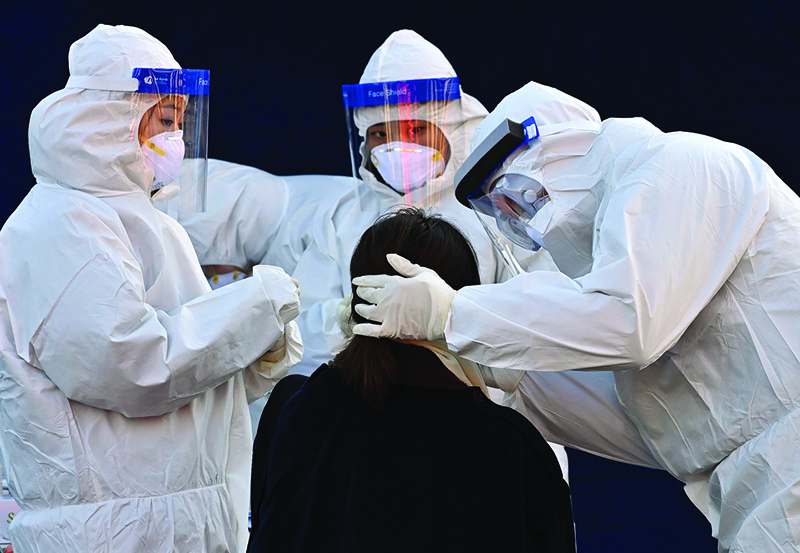 TOPSHOT - A medical staff member wearing protective gear takes a swab from a woman to test for the Covid-19 coronavirus at a temporary testing station outside Seoul station in Seoul on December 14, 2020. (Photo by Jung Yeon-je / AFP)