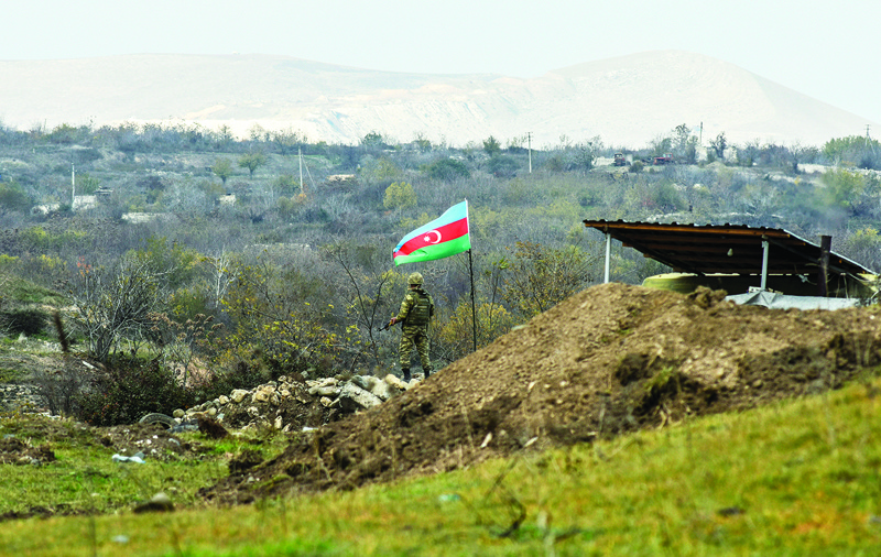 An Azerbaijani soldier stands guard at a checkpoint on a road entering Fizuli from Hadrut on December 2, 2020, a day after Baku's army entered the final district given up by Armenia under a peace deal that ended weeks of fighting over the disputed Nagorno-Karabakh region. (Photo by STRINGER / AFP)