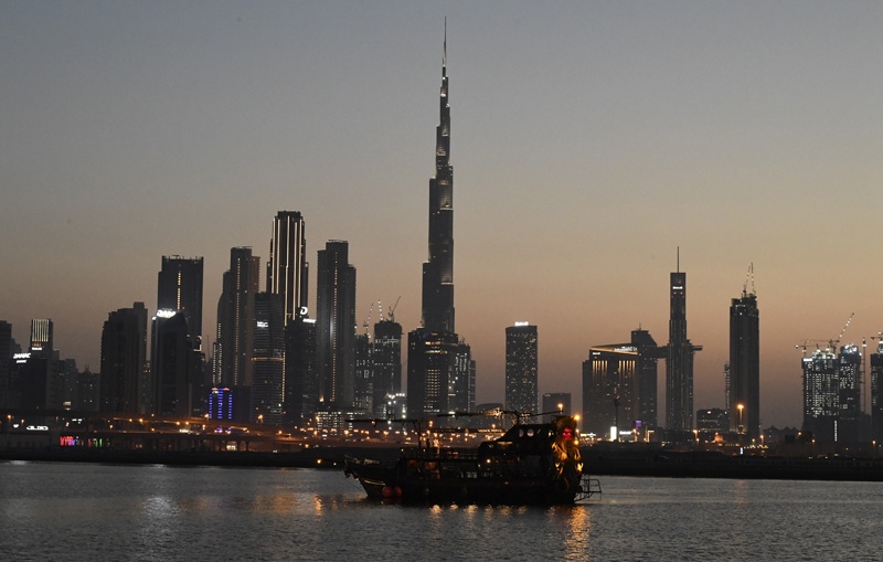 A boat sails at sunset, against the backdrop of Burj Khalifa and high rise buildings, in the Emirati city of Dubai, on May 27, 2020. - The Emirati authorities eased some of the restrictions that were put in place in a bid to stem the spread of the novel coronavirus, allowing some businesses to reopen. (Photo by Karim SAHIB / AFP)