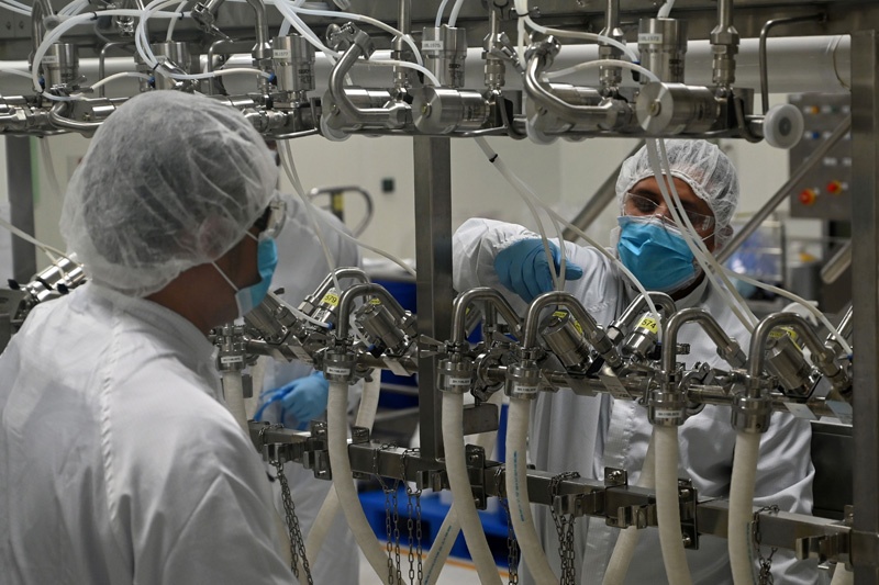 This photograph taken on November 24, 2020 shows biochemists working inside a buffer preparation room used for manufacturing medical products at Takeda Pharmaceuticals (Asia Pacific) in Singapore. - The city-state is on course for its worst ever recession this year but factory activity has held up, thanks partly to countries rushing to stockpile medicines during the pandemic. (Photo by ROSLAN RAHMAN / AFP) / To go with AFP story Singapore-economy-pharmaceutical-health-virus, FOCUS by Martin Abbugao