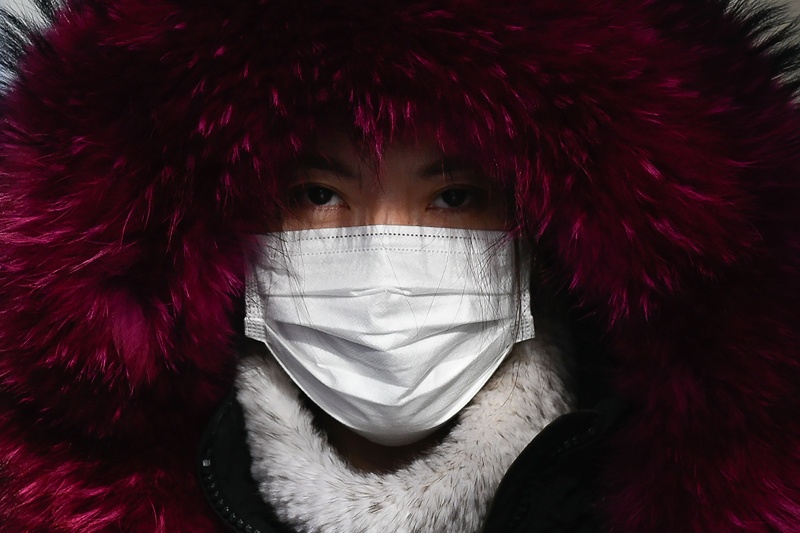 A woman wearing a face mask walks along a street in Beijing on December 23, 2020. (Photo by WANG Zhao / AFP)