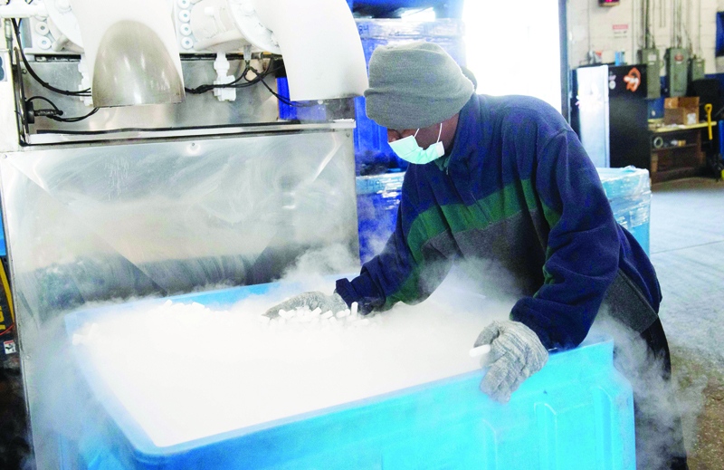An employee makes dry ice pellets at Capitol Carbonic, a dry ice factory, in Baltimore, Maryland, November 20, 2020. - Amid a whipsaw year that saw a surge in demand for its dry ice and a shortage of the carbon dioxide needed to make it, Capitol Carbonic received a call from a prospective customer: Pfizer. The global pharmaceutical giant was on the hunt for the quarter-inch pellets Capitol Carbonic, a six-decade-old family concern, spits out of a machine resembling a giant spaghetti maker in a Baltimore warehouse -- exactly what Pfizer needs to keep its Covid-19 vaccine at just the right, very chilly, temperature. (Photo by SAUL LOEB / AFP)