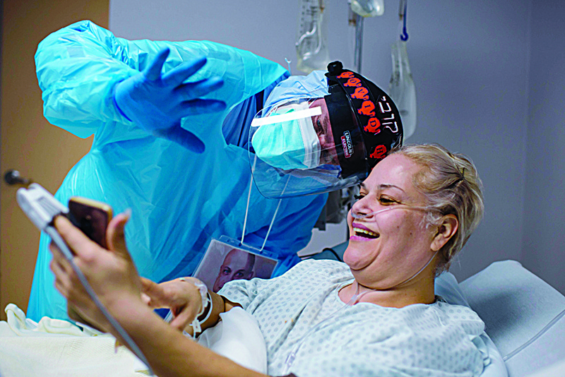 Chief of Staff Doctor Joseph Varon smiles and waves to Gloria Garcia's family as she video calls them from the Covid-19 ward at United Memorial Medical Center in Houston, Texas on December 4, 2020. - Joseph Varon, a doctor treating coronavirus patients at a Texas hospital, was working his 252nd day in a row when he spotted a distraught elderly man in the Covid-19 intensive care unit (ICU). Varon's comforting embrace of the white-haired man on Thanksgiving Day was captured by a photographer for Getty Images and has gone viral around the world. (Photo by Mark Felix / AFP)