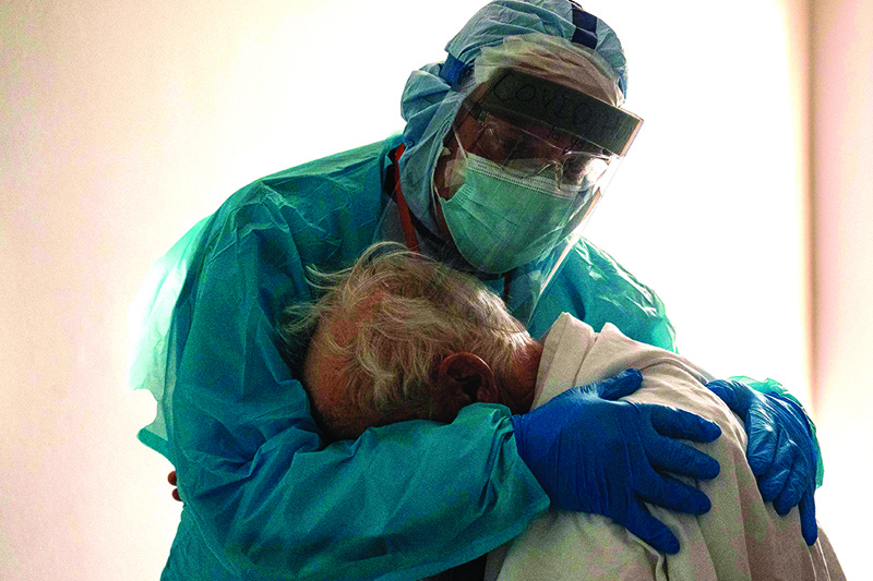 (FILES) In this file photo taken on November 25, 2020 Dr. Joseph Varon hugs and comforts a patient in the COVID-19 intensive care unit (ICU) during Thanksgiving at the United Memorial Medical Center in Houston, Texas. According to reports, Texas has reached over 1,220,000 cases, including over 21,500 deaths. - Joseph Varon, a doctor treating coronavirus patients at a Texas hospital, was working his 252nd day in a row when he spotted a distraught elderly man in the Covid-19 intensive care unit (ICU). (Photo by Go Nakamura / GETTY IMAGES NORTH AMERICA / AFP)