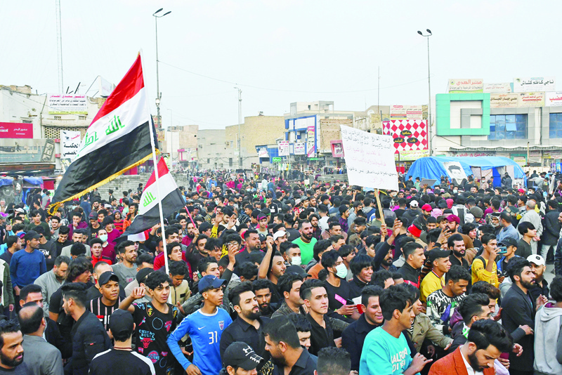 Iraqi demonstrators lift national flags as they gather in Habboubi Square in the southern city of Nasiriyah in Dhi Qar province, on December 4, 2020, to express anger after followers of Shiite cleric Moqtada Sadr clashed with young protesters lately. (Photo by Asaad NIAZI / AFP)