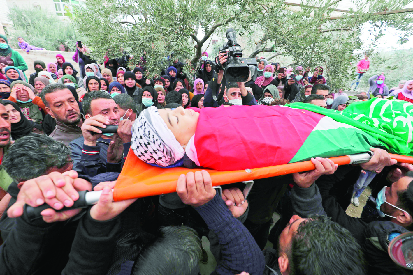 Mourners carry the body of Palestinian teenager Ali Abu Alia during his funeral in the village of Mughayir near Ramallah in the Israeli-occupied West Bank, on December 5, 2020. - A Palestinian teenager was killed in clashes with the Israeli army on the sidelines of a protest in the occupied West Bank, the Palestinian health ministry said. (Photo by ABBAS MOMANI / AFP)