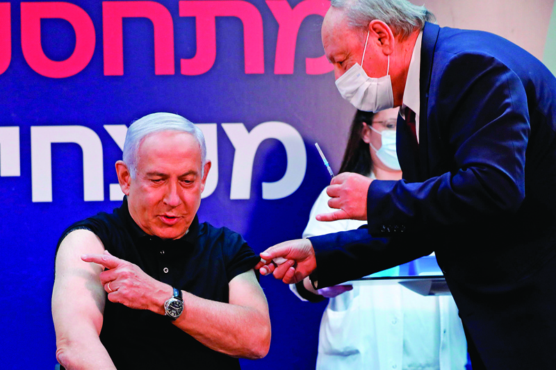 Israeli Prime Minister Benjamin Netanyahu gets ready to receive a coronavirus vaccine at the Sheba Medical Center, the country's largest hospital, in Ramat Gan near the coastal city of Tel Aviv, on December 19, 2020. - Netanyahu, 71, and Israel's health minister were injected with the Pfizer-BioNTech vaccine live on TV at Sheba Medical Center. Each recipient must receive a booster shot in three weeks for optimal protection from the novel coronavirus. (Photo by AMIR COHEN / POOL / AFP)