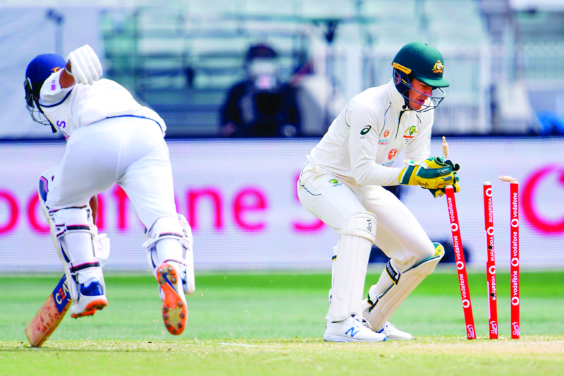 TOPSHOT - Australia's wicketkeeper Tim Paine (R) runs out India's batsman Ajinkya Rahane (L) on the third day of the second cricket Test match between Australia and India at the MCG in Melbourne on December 28, 2020. (Photo by WILLIAM WEST / AFP) / --IMAGE RESTRICTED TO EDITORIAL USE - STRICTLY NO COMMERCIAL USE--