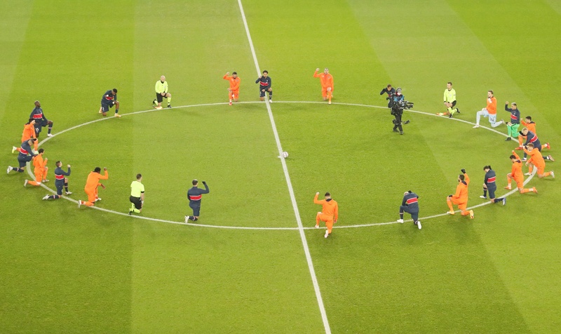 TOPSHOT - Football players and referees kneel on the pitch against racism before the UEFA Champions League group H football match between Paris Saint-Germain (PSG) and Istanbul Basaksehir FK at the Parc des Princes stadium in Paris, on December 9, 2020. (Photo by XAVIER LAINE / POOL / AFP)