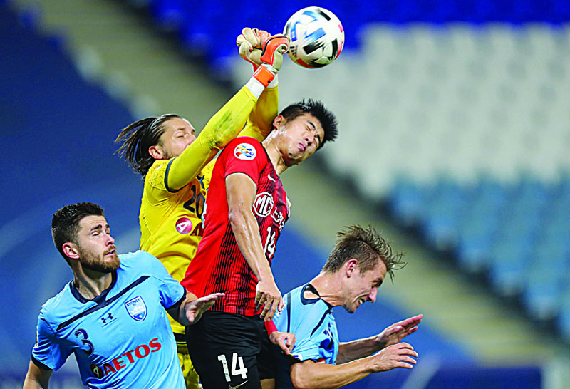 Sydney's goalkeeper Thomas Heward-Belle (C-L) punches the ball ahead of SIPG's forward Li Shenglong (C-R) during the AFC Champions League group H football match between China's Shanghai SIPG and Australia's Sydney FC on December 1, 2020 at the al-Janoub Stadium in the Qatari city of Al Wakrah. (Photo by KARIM JAAFAR / AFP)