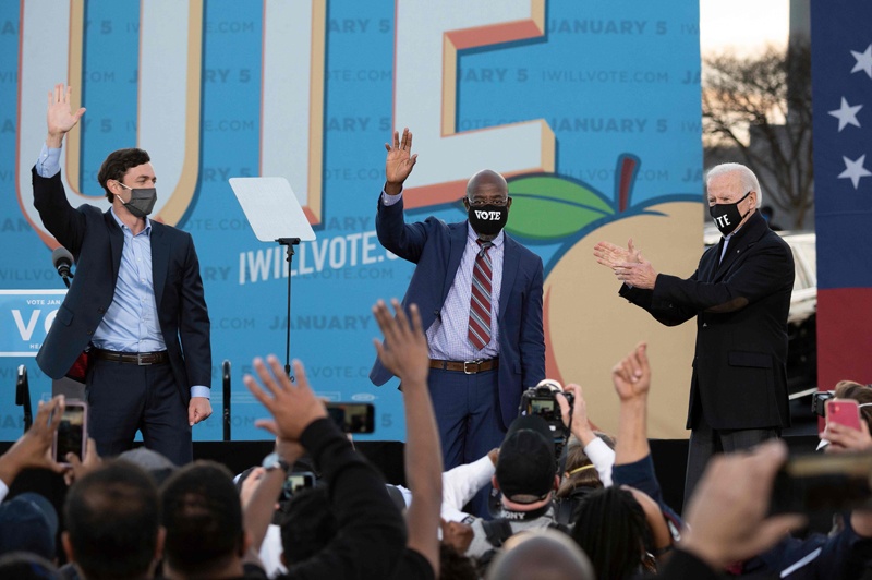 Democratic candidates for Senate Jon Ossoff (L), Raphael Warnock (C) and US President-elect Joe Biden (R) stand on stage during a rally outside Center Parc Stadium in Atlanta, Georgia, on January 4, 2021. - President Donald Trump, still seeking ways to reverse his election defeat, and President-elect Joe Biden converge on Georgia on Monday for dueling rallies on the eve of runoff votes that will decide control of the US Senate. Trump, a day after the release of a bombshell recording in which he pressures Georgia officials to overturn his November 3 election loss in the southern state, is to hold a rally in the northwest city of Dalton in support of Republican incumbent senators Kelly Loeffler and David Perdue. Biden, who takes over the White House on January 20, is to campaign in Atlanta, the Georgia capital, for the Democratic challengers, Raphael Warnock and Jon Ossoff. (Photo by JIM WATSON / AFP)