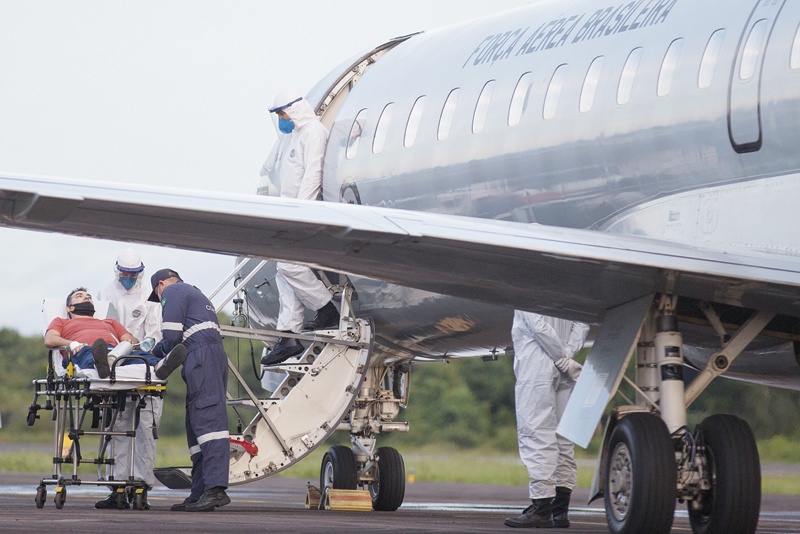 A COVID-19 patient, one of 12 to be transferred in a military airplane, is assisted by medical staff at the Ponta Pelada airport in Manaus, Amazonas State, Brazil, Friday amid the novel coronavirus pandemic. - AFPn