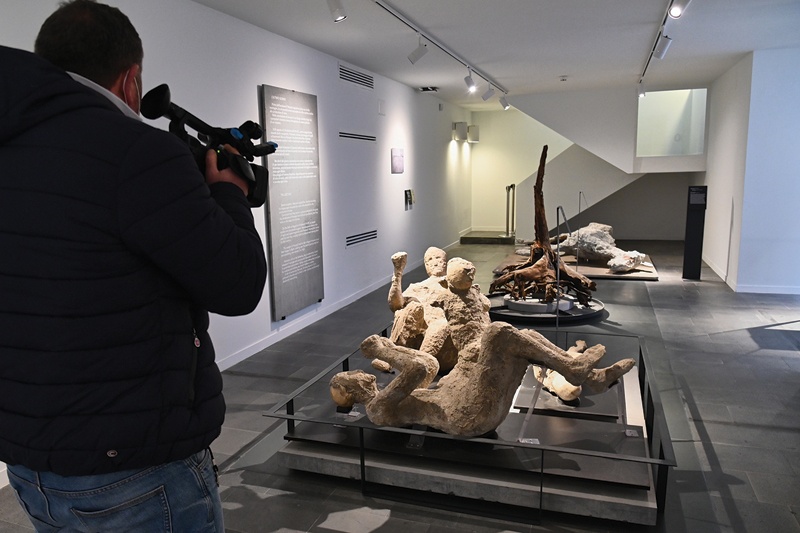 A visitor films copies of casts of a man with a baby, an adult and a baby, at the Antiquarium museum.n