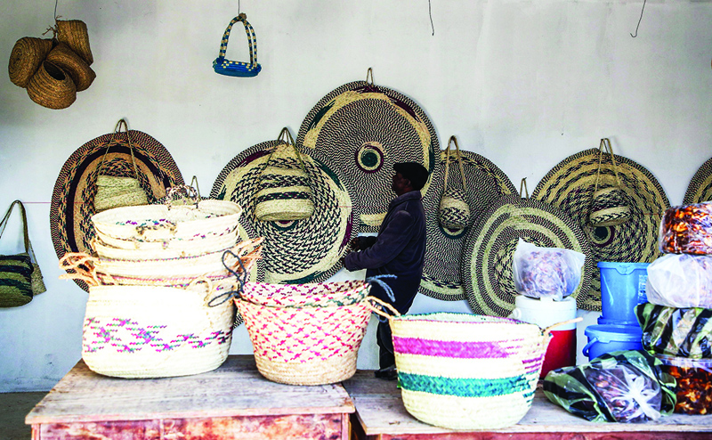 A man inspects palm wicker products on display, made by Haleema Mohamed.