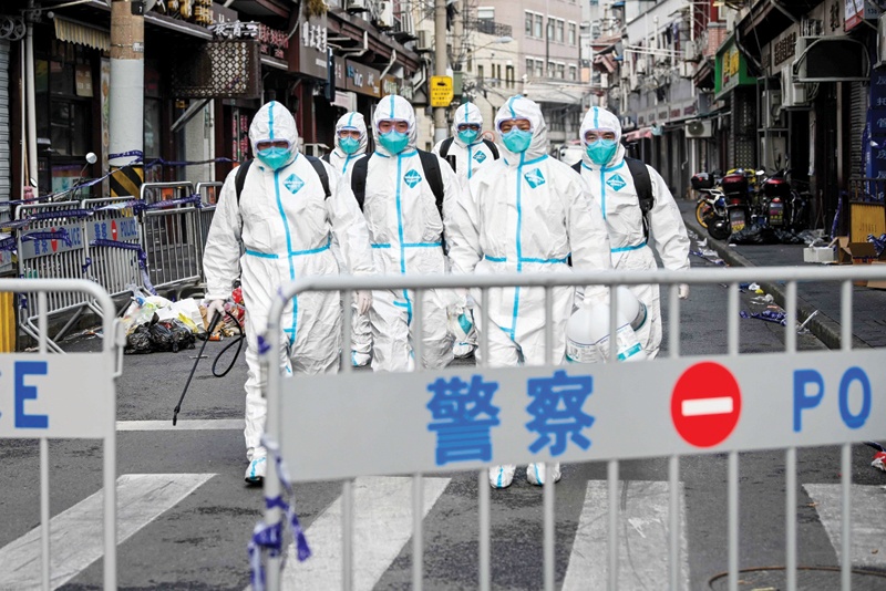 SHANGHAI: Health workers in protective gear walk out from a blocked off area after spraying disinfectant in Shanghai's Huangpu district yesterday.-AFP n