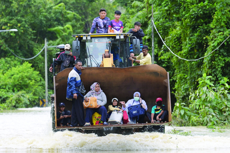 TOPSHOT - Residents ride a digger vehicle through floodwaters following heavy monsoon downpour in Lanchang, Malaysia's Pahang state on January 6, 2021. (Photo by Mohd RASFAN / AFP)