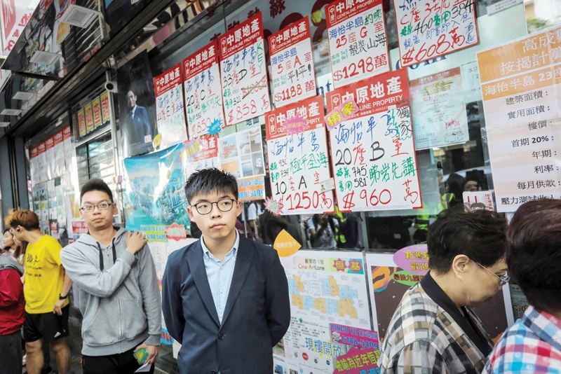 HONG KONG: In this file photo taken on November 24, 2019 pro-democracy activist Joshua Wong (center), who was disqualified from running, queues up to cast his vote during district council elections in the South Horizons district in Hong Kong. - AFPn