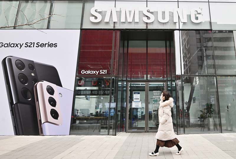 SEOUL: A woman walks past an advertisement for the Samsung Galaxy S21 smartphone at a Samsung Electronics store in Seoul yesterday after the company reported its fourth-quarter net profits up by more than a quarter year-on-year. - AFPn