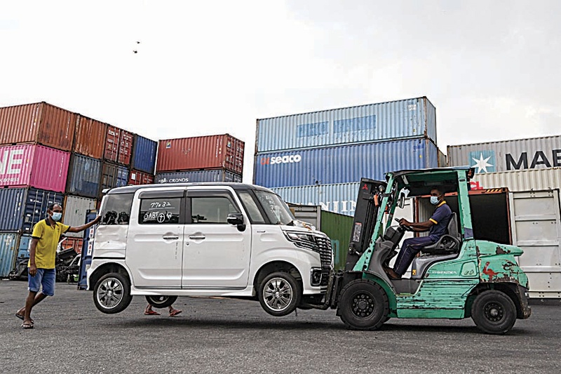 COLOMBO: Workers unload vehicles imported illegally into Sri Lanka at a warehouse as a ban on non-essential imports remains in place, in Colombo yesterday. - AFP