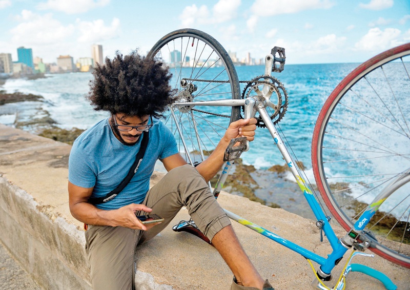 HAVANA: Cuban Yasser Gonzalez uses his cell phone to connect to the Internet at the Malecon on Nov 24, 2020. - AFP n