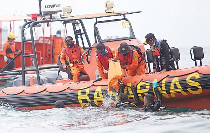 Divers bringing up a bag filled with body parts to a search and rescue boat off the coast north of Jakarta yesterday. - AFP nn