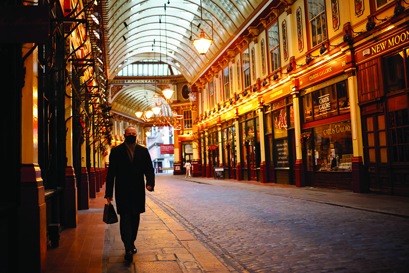 A lone pedestrian walks through Leadenhall market in the City of London, as Britain enters a national lockdown in London on January 5, 2021. - England's six-week lockdown, which began at midnight, emulates the first national coronavirus curbs in place from March to June -- but goes further than another instituted in November when schools remained open. Authorities in Wales, Scotland and Northern Ireland have all taken similar measures, putting the UK as a whole in lockdown. (Photo by Tolga Akmen / AFP)