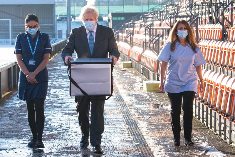 LONDON: Prime Minister Boris Johnson carries Oxford/AstraZeneca COVID 19 vaccines for distribution during a visit to Barnet FC's ground at The Hive, north London, which is being used as a coronavirus vaccination center yesterday.-AFP nn