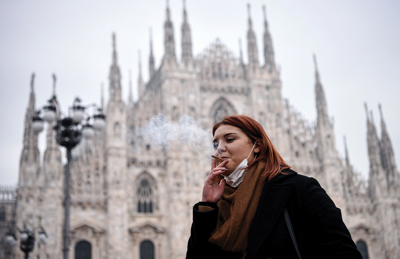 MILAN: A woman smokes a cigarette on Piazza del Duomo in Milan as it became the first Italian city to introduce an outdoor smoking ban.-AFP n