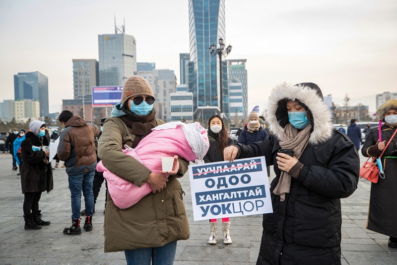 ULAANBAATAR: A protester carrying a 2-month-old baby while another holds a sign urging officials of the national emergency commission to resign, during a rally at Sukhbaatar square in Ulaanbaatar, the capital of Mongolia. - AFPn