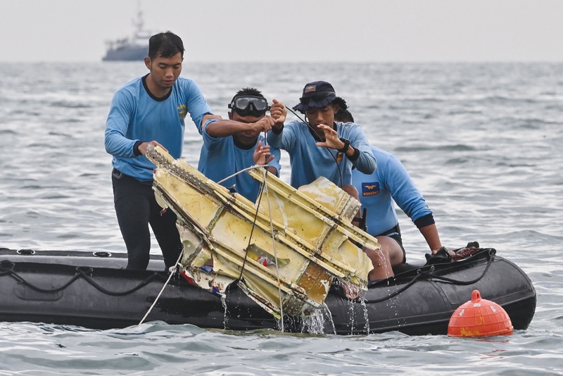Indonesian navy divers hold wreckage from Sriwijaya Air flight SJY182 during a search and rescue operation at sea near Lancang island yesterday. - AFP n