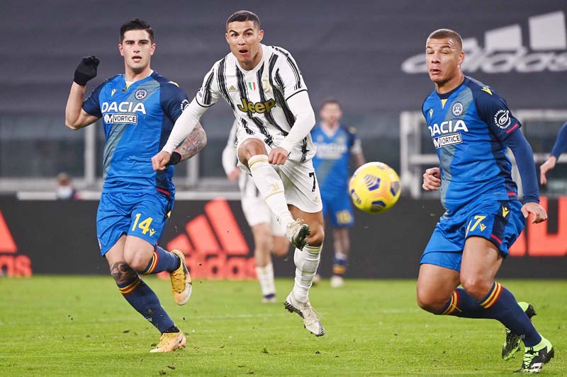 Juventus' Portuguese forward Cristiano Ronaldo (C) shoots to score the opening goal despite Udinese's Italian defender Kevin Bonifazi (L) and Udinese's French defender Sebastian De Maio during the Italian Serie A football match Juventus vs Udinese on January 3, 2021 at the Juventus stadium in Turin. (Photo by Marco BERTORELLO / AFP)