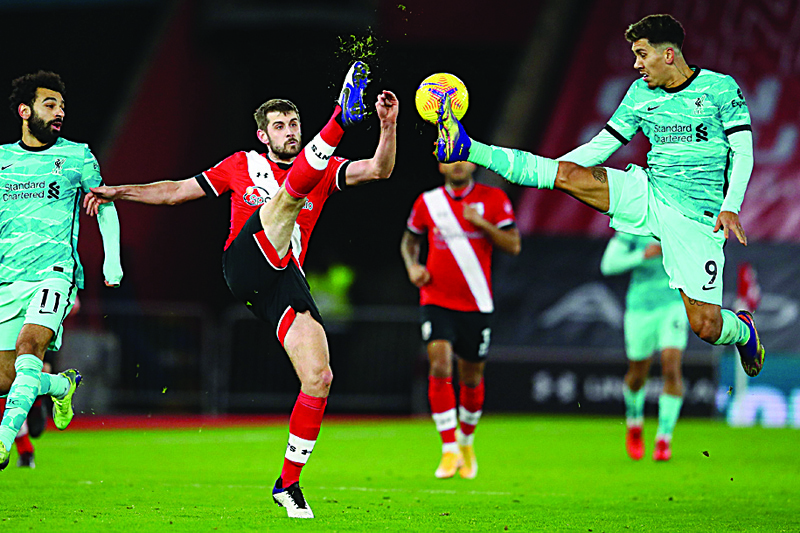 TOPSHOT - Southampton's English defender Jack Stephens (C) vies with Liverpool's Brazilian midfielder Roberto Firmino (R) during the English Premier League football match between Southampton and Liverpool at St Mary's Stadium in Southampton, southern England on January 4, 2021. (Photo by Michael Steele / POOL / AFP) / RESTRICTED TO EDITORIAL USE. No use with unauthorized audio, video, data, fixture lists, club/league logos or 'live' services. Online in-match use limited to 120 images. An additional 40 images may be used in extra time. No video emulation. Social media in-match use limited to 120 images. An additional 40 images may be used in extra time. No use in betting publications, games or single club/league/player publications. /