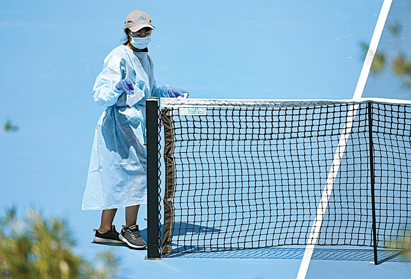 MELBOURNE: A cleaner wipes down the net after a player's practise session in Melbourne on January 25, 2021, with players allowed to train while serving quarantine for two weeks ahead of the Australian Open tennis tournament. - AFPn