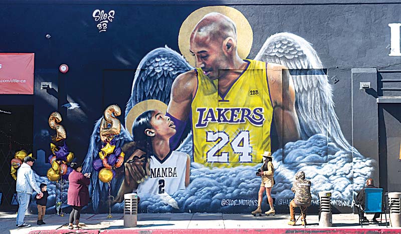 LOS ANGELES: People gather in front of a mural of former Los Angeles Laker Kobe Bryant and his daughter Gianna, both with a set of wings, by artist sloe_motions displayed on a wall in downtown Los Angeles, California on Tuesday as people mark the one-year death anniversary of Kobe Bryant. - AFPn