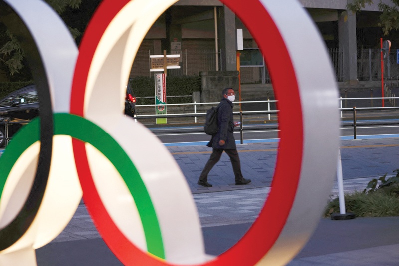 TOKYO: A man wearing a face mask walks past Olympic Rings in Tokyo on January 8, 2021. - AFPn