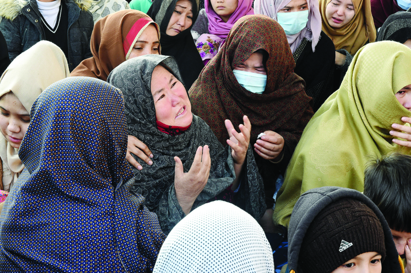 Mourners from the Shiite Hazara community react as they gather with the coffins of the miners who were killed in an attack by gunmen in the mountainous Machh area, during a sit-in protest at the eastern bypass, on the outskits of Quetta on January 4, 2021. - Thousands of mourners from Pakistan's minority Shiite community on January 4 protested alongside the bodies of miners killed in an attack claimed by the Islamic State group. (Photo by Banaras KHAN / AFP)