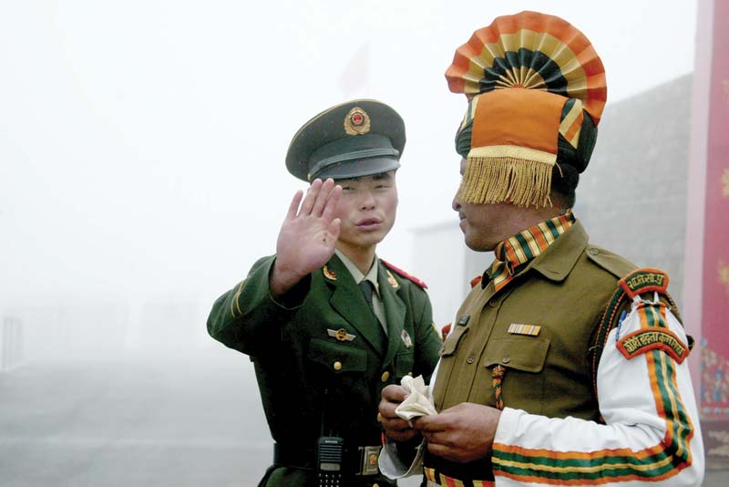 In this file photo a Chinese soldier gestures as he stands near an Indian soldier on the Chinese side of the ancient Nathu La border crossing between India and China.-AFP n