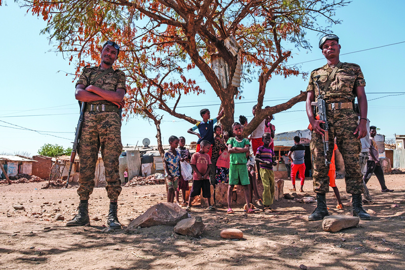 Ethiopian Army soldiers stand as a children stand behind them at Mai Aini Refugee camp, in Ethiopia.-AFPn