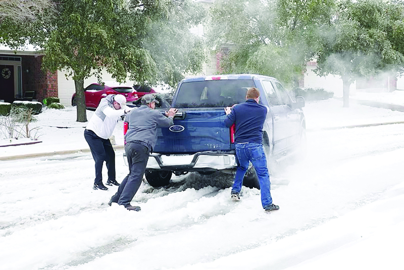 ROUND ROCK: Residents help a pickup driver get out of ice on the road in Round Rock, Texas, on Wednesday after a winter storm. - AFPn