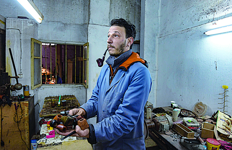 Anis Bouchnak tries a briar wood pipe that he made at his workshop in the northwestern Tunisian coastal town of Tabarka.-AFP photosn