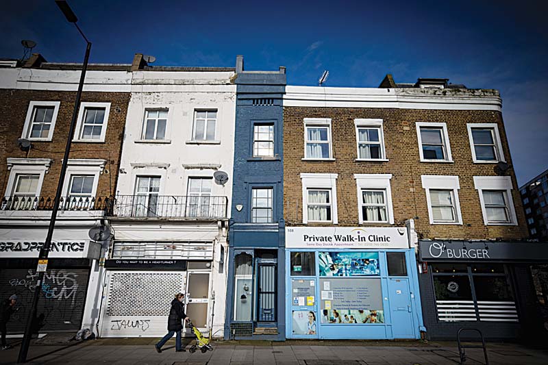 A pedestrian passes the front of what is dubbed 'London's thinnest house' (painted blue) in west London.-AFP photosn