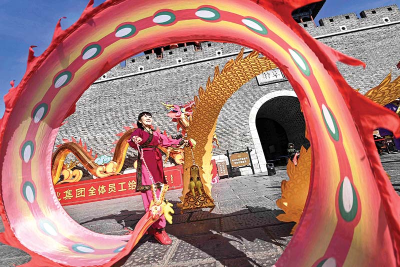 A folk artist performs a diabolo dragon dance, a traditional Chinese performance, in front of one of the buildings at the Qingshan Ancient Town in Qingzhou, in eastern China’s Shandong province yesterday.—AFP photosn