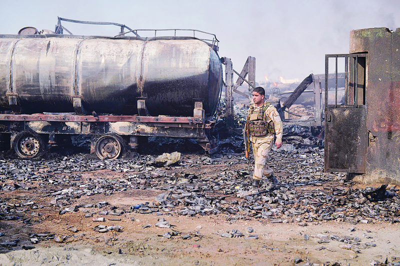 A security forces personnel walks amidst wreckage of gas tankers after a fire accident at Islam Qala on the outskirts of Herat, in the border between Afghanistan and Iran on February 14, 2021. (Photo by HOSHANG HASHIMI / AFP)