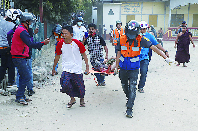 MANDALAY: A wounded man is carried on a stretcher by a medical team after security forces opened fire on protesters during a demonstration against the military coup in Mandalay yesterday.-AFPn